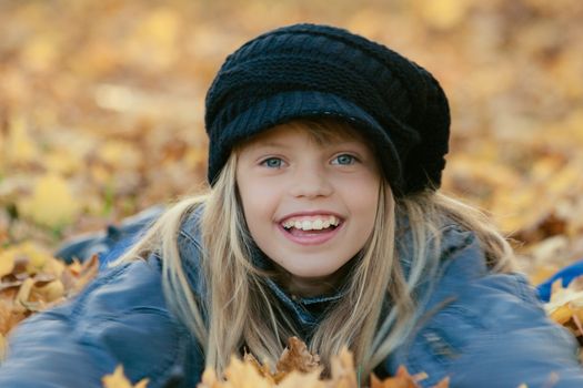 Little smiling girl  lying in fall leaves