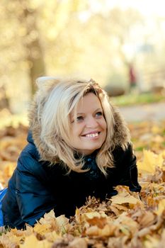 Smiling woman lying  on fall leaves