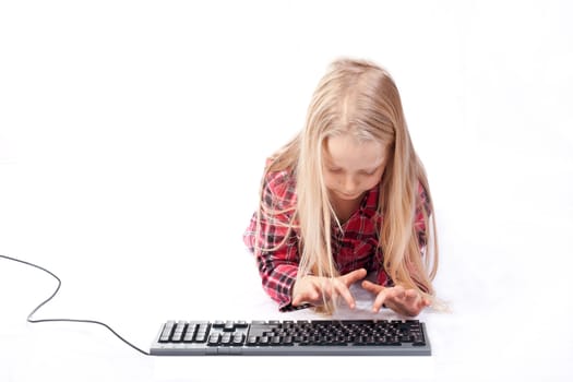 Little girl writes on a computer keyboard against white background
