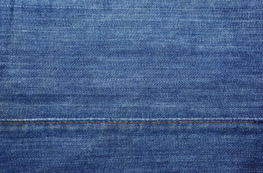 Blue jeans with yellow stitches as textile abstract backdrop or background.