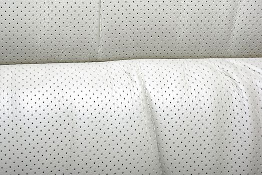High quality perforated beige car leather textured background.