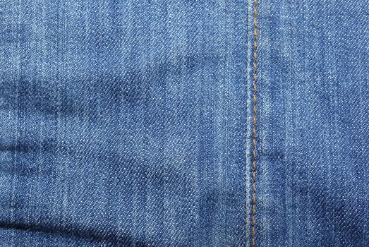 Blue jeans with vertical yellow stitches abstract textured background.