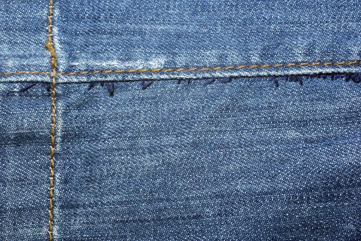 Blue worn jeans with yellow stitches close up. Background or backdrop.