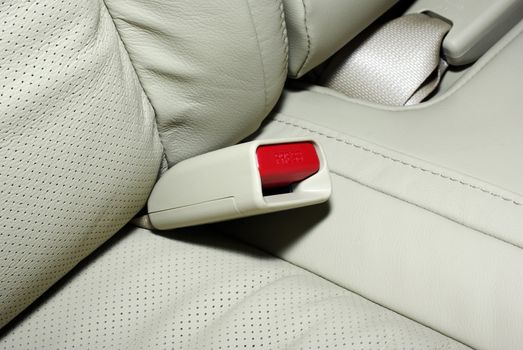 Seat belt plastic mechanism with red press button. Beige expensive leather. Interior of modern japanese car.