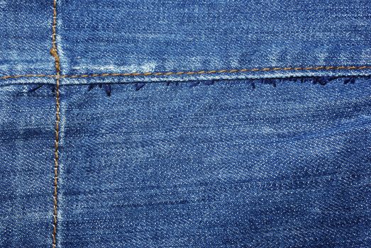 Blue jeans with yellow stitches abstract textile background.