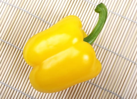 Yellow bell pepper laying on japanese wooden mat.