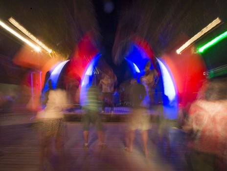 People in colorful nightclub dancing to loud bass music