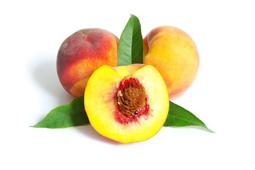 fresh peach fruits with green leaves isolated on white