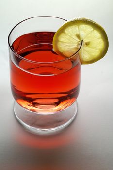 Glass of red liquid (wine,  tea, etc.) with lemon slice (vertical)