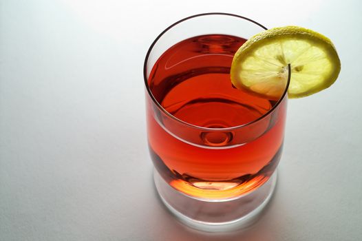 Glass of red liquid (wine,  tea, etc.) with lemon slice (horizontal)