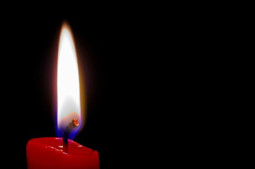 Red (isolated)  lighted candle in black background with space intentionally left blank for text.