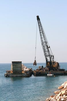 floating crane unloading flat barge full of stones