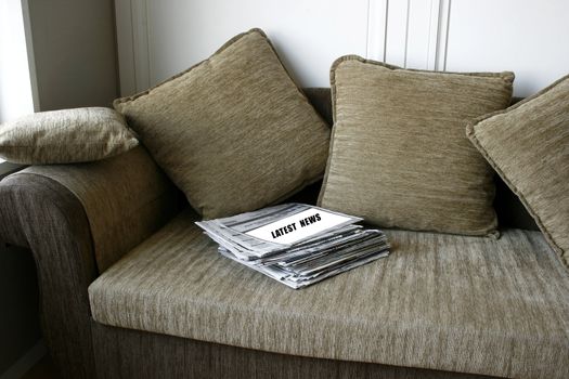 Latest News on a pile of Newspaper on a cozy sofa