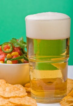 Cold glass of beer with salsa and chips.