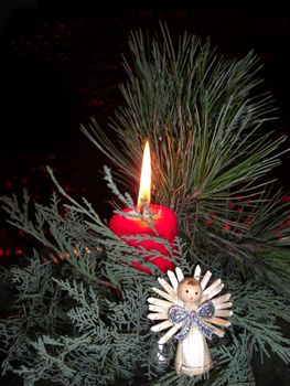 candle arranged with fir and a small angel