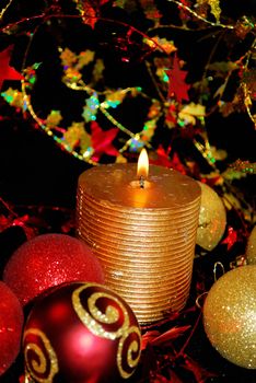 Gld candle with color christmas ornaments are on the magic bacground. 
