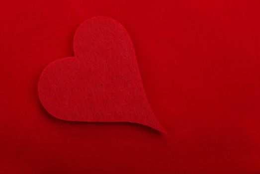 Red textile heart isolated on red background. Empty space for your design.