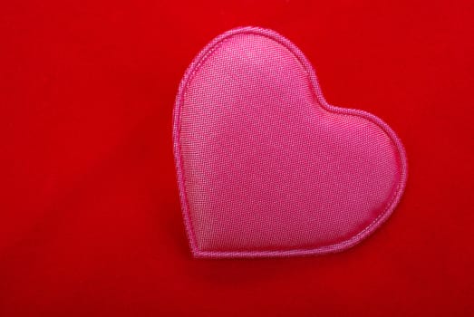 Pink heart close up isolated on red textured background.