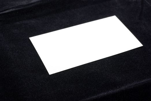 White business card isolated on black velvet background. Empty space for your design.