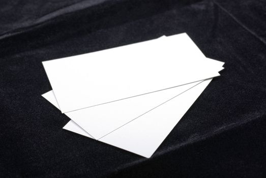 Three white business cards isolated on black velvet background. Empty space for your design.