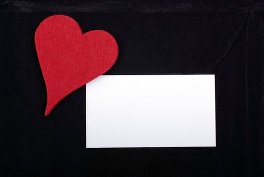 Red heart and empty card isolated on black velvet background. Empty space for your text or design.