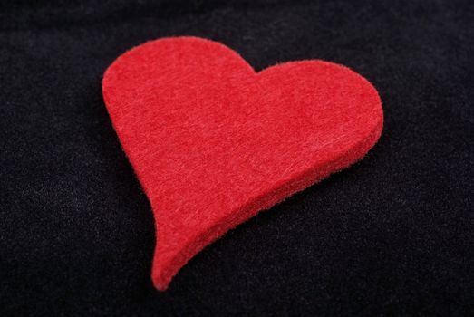 Close up of red heart isolated on black velvet background. Studio shot.