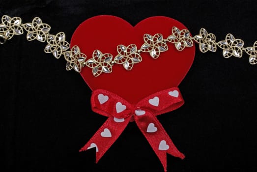 Golden armlet with red heart isolated on black velvet background.