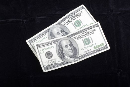 Two hundred dollars banknotes isolated on black velvet background.