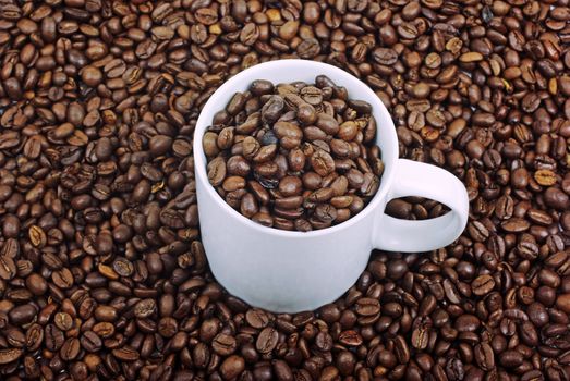 White coffee cup on brown roasted beans as background.