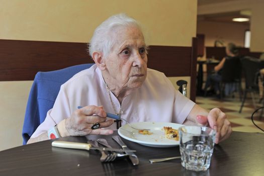 senior woman smiling and eating in a  retirement facility