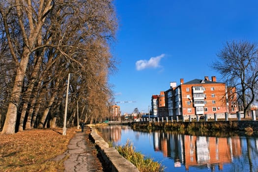 City house above the river canal near the old park. Late autumn urban landscape