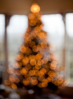 Deliberated blurred Christmas tree decorated with silver and white ribbons to get the out of focus images of the lights in family home