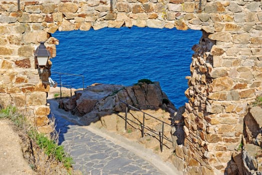 Pass in fortress made of stone as natural frame. Tossa de Mar, Spain.