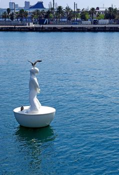 A buoy like a man with seagulls on it in Barcelona harbour.