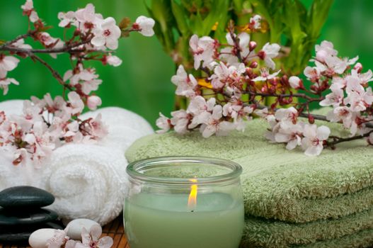 Spa concept with aromatic candle, cotton towels, and healing pebbles