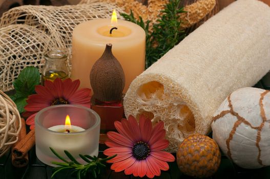 Spa concept with aromatic candles, herbs, beautiful daisies, massage oil and loofah