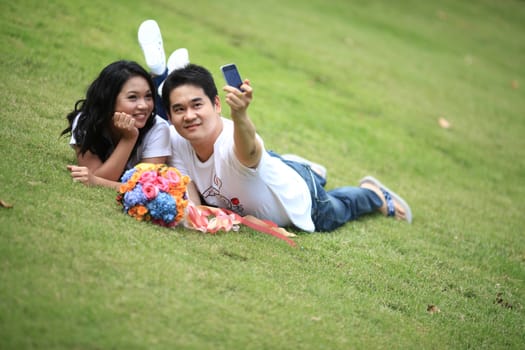 ypung couples laying on grass and taking self portrait with mobile phone