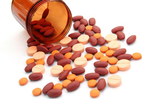 Persepctive of Open pill bottle with medicine spilling out isolated on white background