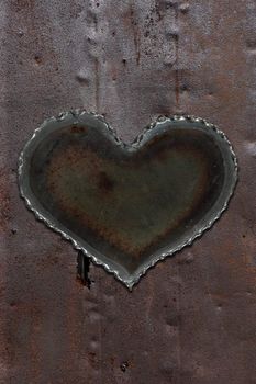 Photo of a metal heart attached to a sheet of rusty sheet metal.