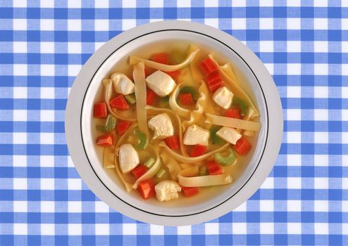 Chicken soup with vegetables isolated on a blue white bakcground