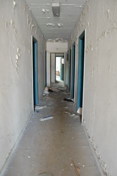 Long empty hallway and doors in abandoned building.