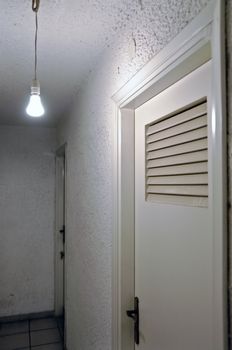Bare light bulb and doors in underground hallway.