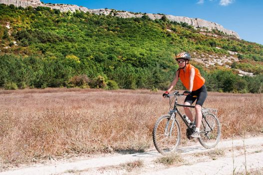 Active bicyclist riding at the countryside against moontain