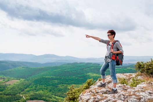 girl standing on a mountain and shows on the valley