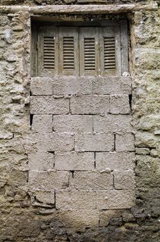 Bricked up window and textured wall of a derelict house.