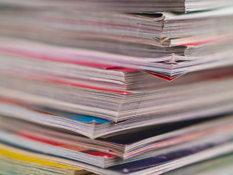 An uneven stack of magazines filling the frame from top to bottom focus on corner edge