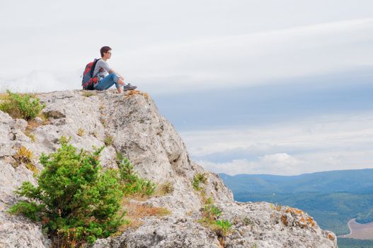 irl sitting on a mountain and looking on the valley