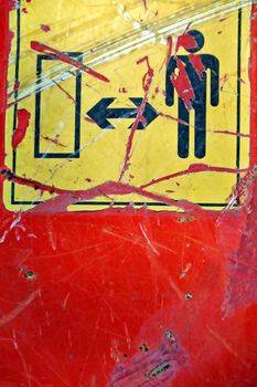 Weathered industrial safety sign on rusty construction machinery metal surface.