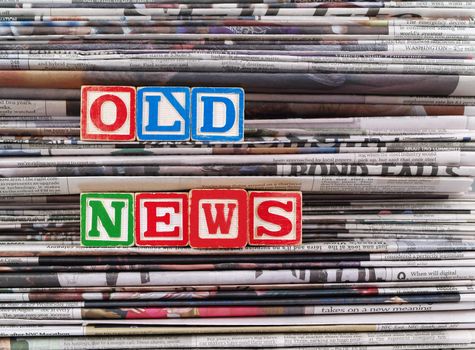 Old newspapers stacked and "Old News" is written in Block Letters 