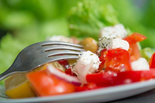 Tasty Greek salad on a plate with a fork